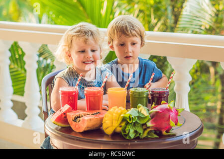 Kinder trinken Bunte gesunde Smoothies.. Wassermelone, Papaya, Mango, Spinat und Dragon Obst. Smoothies, Säfte, Getränke, Getränke Vielfalt mit frischen Früchten auf einem Holztisch Stockfoto