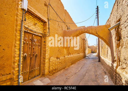 Die schäbige Straße der alten Stadt mit mittelalterlichen Holztür, bröckelt Adobe Wände, gebogene kuche Durchgang und enge Straße, Yazd, Iran. Stockfoto