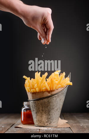 Hand streut eine Prise Salz Stockfoto