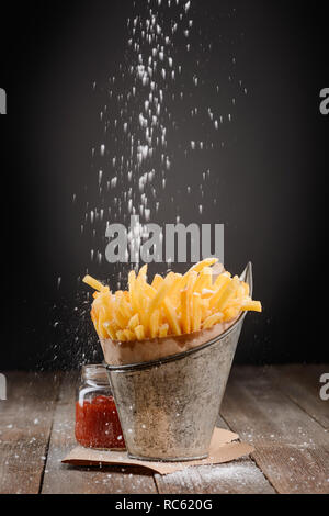 Salz streuen auf Pommes Frites Stockfoto
