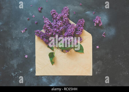 Rosa Flieder in Umschlag auf dunkle vintage Tabelle. Konzept. Blick von oben. Grußansage für Frauen oder Mütter Tag. Kreatives Konzept. Stockfoto