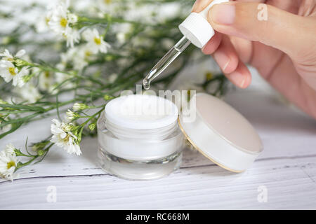 Organic Natural skincare Konzept. Öffnen leer kosmetische Creme Glas mit weisser Creme Textur innen Frauen hand Glas dropper und für Dermatologen Stockfoto