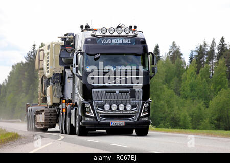 Uurainen Finnland - Juni 15, 2018: Schwarz Volvo FH 16 Auflieger Hols industrielle Ausrüstung als große Last Road Transport entlang der Autobahn 4 im Sommer. Stockfoto