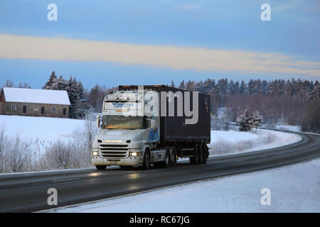 Salo, Finnland - Januar 19, 2018: Weiß Scania 124L LKW Transport K. Lindholm zieht Anhänger auf der Autobahn in der Dämmerung durch die winterliche Landschaft im ländlichen Raum Stockfoto