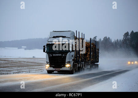 Salo, Finnland - Dezember 21, 2018: Silber Scania R730 Streamline logging Truck hols Last auf verschneiter Straße an einem Winterabend im Süden Finnlands. Stockfoto