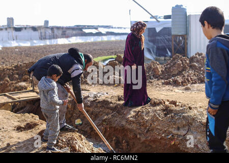 Januar 13, 2019 - Libanon - eine syrische Flüchtlinge gräbt ein Kanal Hochwasser von einem in der Nähe gelegenen Fluss von Zelte umleiten.. Storm Norma betroffen Tausende von syrischen Flüchtlinge leben in prekären Bedingungen in der Libanesischen Bekaa-tal. Sie sind jetzt gezwungen, die für eine andere Sturm, die sich vorbereitet werden. (Bild: © adib Chowdhury/SOPA Bilder über ZUMA Draht) Stockfoto