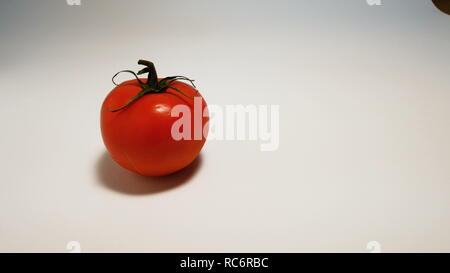 Hand spritzt eine Spritze mit grüner Flüssigkeit GVO in eine Tomate auf weißem Hintergrund Stockfoto