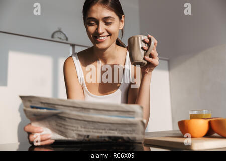 Lächelnden jungen Mädchen stehen in der Küche am Morgen, lesen Zeitung, Tee trinken. Stockfoto