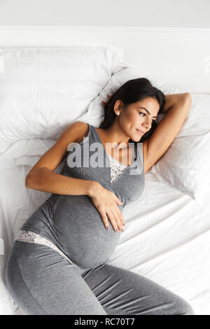 Bild von einer erstaunlichen gesunde schwangere Frau zuhause zu Hause liegt im Bett. Stockfoto