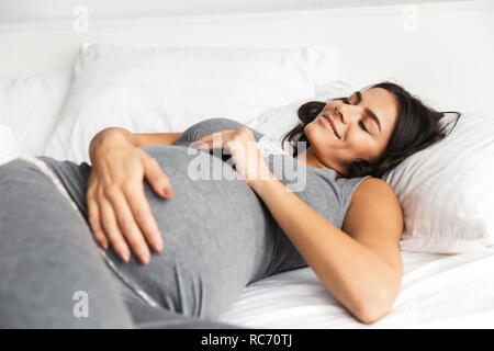 Bild von einer erstaunlichen gesunde schwangere Frau zuhause zu Hause liegt im Bett. Stockfoto
