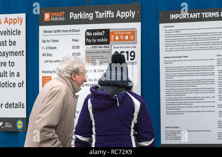 Ein älteres Ehepaar am Parkplatz Regeln auf Schildern in den Fistral Beach Parkplatz in Newquay Cornwall suchen. Stockfoto