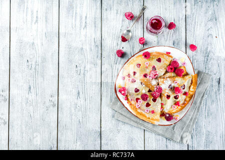 Idee für den Valentinstag Überraschung. Süße Pfannkuchen Crepes mit Berry Sauce und herzförmige Ausschnitte. Romantischer Valentinstag Frühstück. Auf hölzernen Tisch, Stockfoto