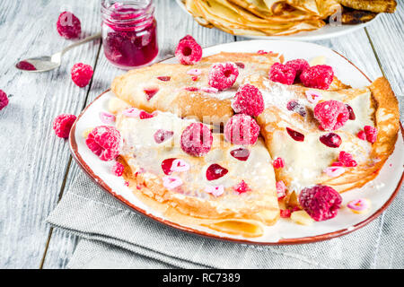 Idee für den Valentinstag Überraschung. Süße Pfannkuchen Crepes mit Berry Sauce und herzförmige Ausschnitte. Romantischer Valentinstag Frühstück. Auf hölzernen Tisch, Stockfoto