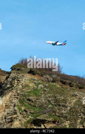 Ein Jet2 Urlaub Boeing 737 fliegen über Klippen am Watergate Bay in Cornwall. Stockfoto