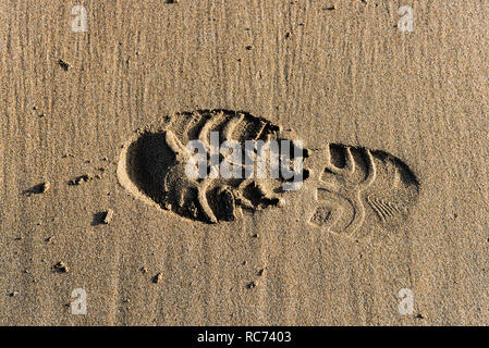 Ein Abdruck einer Shoeprint in feuchten Sand am Strand. Stockfoto