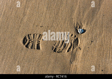 Ein Abdruck einer Shoeprint in feuchten Sand am Strand. Stockfoto