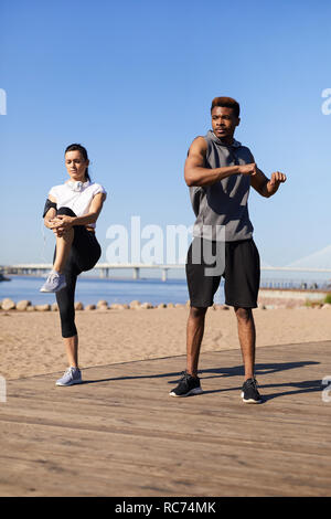 Paar am Strand dehnen Stockfoto