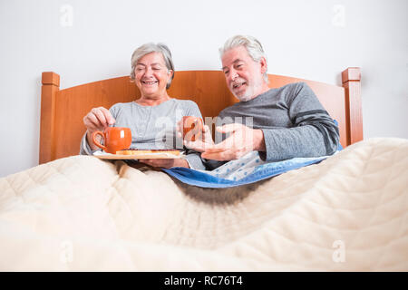 Paar erwachsener Senior zu Hause Frühstück zusammen im Bett am Morgen - Indoor Aktivitäten für verheiratete Personen - Grundriss und Mann und Frau hav Stockfoto