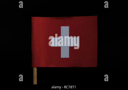 Eine wunderschöne und ursprüngliche nationale Flagge der Schweiz auf Zahnstocher auf schwarzem Hintergrund. Eine quadratische Flagge mit einem weißen Kreuz in der Mitte und Hintergrund Stockfoto