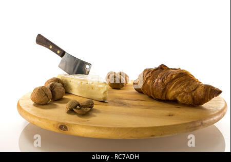 Holz- drehbare Platte mit französischem Käse genannt Brie mit einem Messer und einem französischen Croissant und Walnüsse und Mandeln Stockfoto