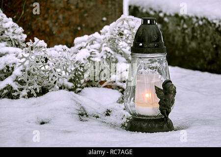 Laterne mit Kerze am Grab bedeckt mit Schnee im Winter. Stockfoto