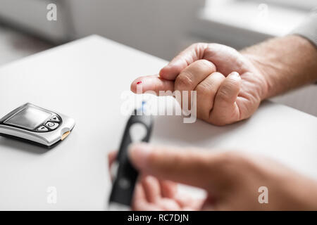 ältere Mann mit Glucometer, die Kontrolle des Blutzuckers Stockfoto