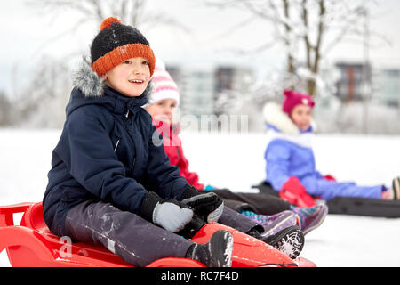Happy Kids rutschen auf Schlitten im Winter Stockfoto