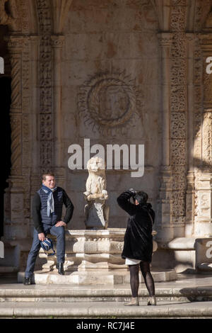 Touristen fotografieren neben einem Brunnen mit einem steinernen Löwen innerhalb des Jeronimos Kloster (Mosteiro dos Jerónimos), Lissabon, Portugal Stockfoto