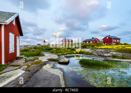 Rote Falun Cottages und Leuchtturm im Hintergrund Stockfoto