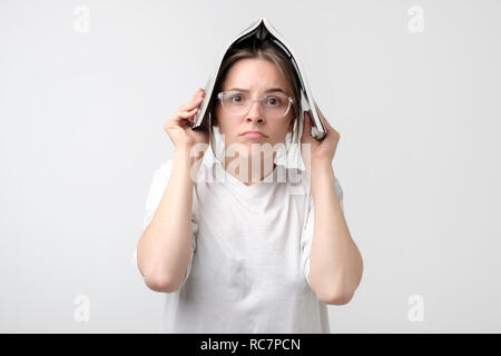 Porträt eines jungen Mädchens während studiyng über Kopf mit Buch. Sie ist müde und Stress. Stockfoto