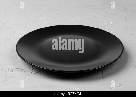 Blick von oben auf die Matte runde Leere schwarze Platte auf grauem Zement Hintergrund Kopie Platz für Sie entwerfen. Perspektive betrachten. Stockfoto