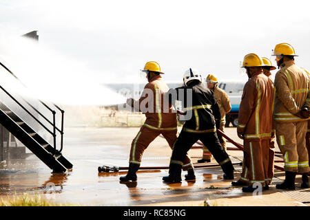 Feuerwehr Training, Feuerwehrleute sprühen Wasser bei Training Service Stockfoto