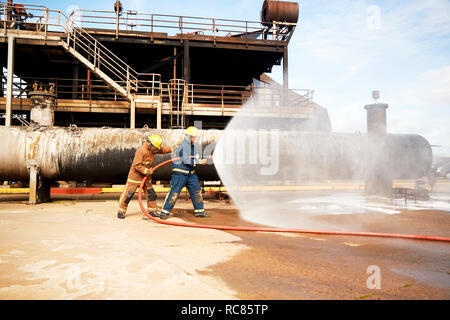 Feuerwehr Training, Feuerwehrleute Sprühwasser aus Feuer, Schlauch am Training Service Stockfoto