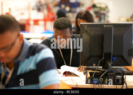 Männliche Studierende an den Schaltern in der Hochschule Klassenzimmer arbeiten Stockfoto