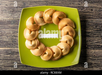 Fortune Cookies mit leeren Papier in der Mitte der grünen Platte auf hölzernen Tisch Stockfoto