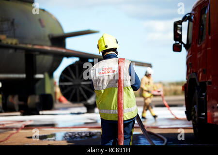 Feuerwehrmann mit Schlauch über die Schulter, Darlington, Großbritannien Stockfoto