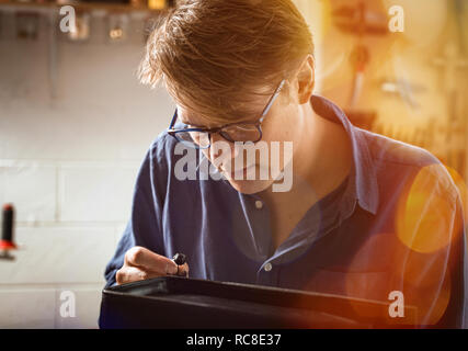 Sattler Anwendung flüssiger Klebstoff Leder Handtasche in Werkstatt, lens flare Stockfoto