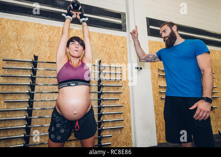 Schwangere Frau mit kettlebell in der Turnhalle Stockfoto