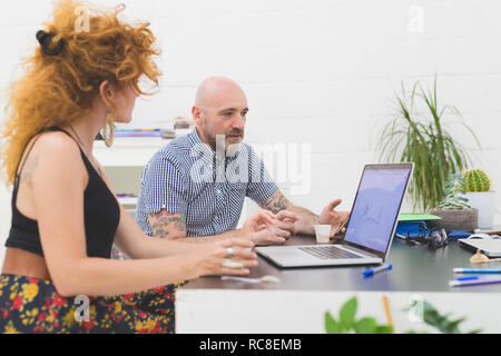 Geschäftsmann und Frau betrachten Laptop im Büro Stockfoto