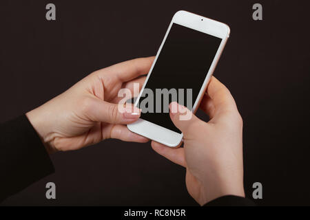 Handy in weibliche Hände auf schwarzem Hintergrund Stockfoto