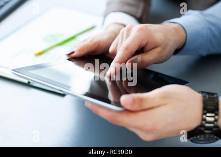 Nahaufnahme der Ein Büroangestellter mit einem Tablet statistische Daten zu analysieren. Stockfoto