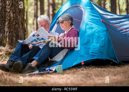 Nach reife Rentnerehepaar enjouying die wilden Camping outdoor im Wald zusammen, die eine Karte auf Papier das nächste Abenteuer Ziel wählen Stockfoto
