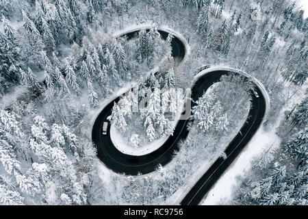 Luftaufnahme von einem Winter Wicklung Landstraße mitten im Wald Stockfoto