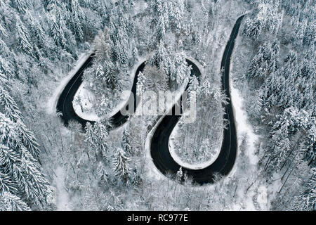 Schwere Schnee auf kurvenreichen Straße in den Wald durch die Berge Stockfoto