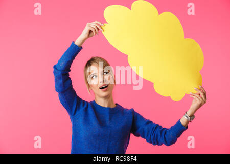 Fröhliche junge blonde Frau mit Pullover stehend über rosa Hintergrund isoliert, Holding leere Sprechblase Stockfoto