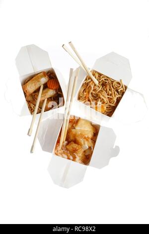 Fast food, verschiedene asiatische Gerichte, Nudeln, Frühlingsrollen und süß und sauer Huhn auf Reis, verpackt, mit Stäbchen Stockfoto