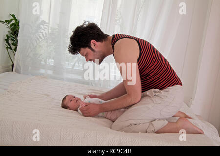 Junger Vater wickelt Baby Stockfoto