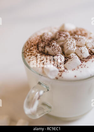 Babyccino - Schlagsahne Milch oder Sahne mit Kakao oder Zimt Pulver und Eibisch. Idee und Rezept für Kinder trinken - warme Sahne Milch, ohne Kaffee. Babyccino in Glas Schale auf Marmortisch. Platz kopieren Stockfoto