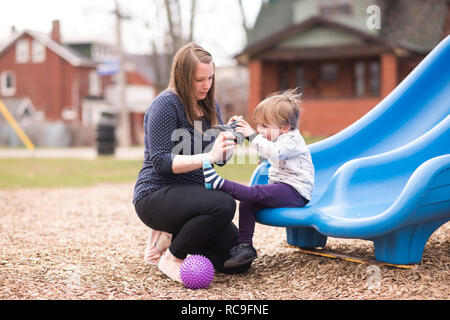 Mutter hilft Sohn mit Schuh auf Folie Stockfoto