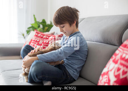 Süße kleine Jungen Füttern von Kaninchen mit Apple zu Hause im sonnigen Zimmer Stockfoto